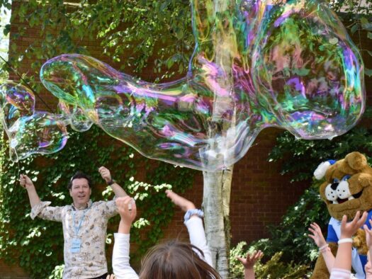 Jon creates huge bubbles for a crowd at a festival using tent poles as wands.